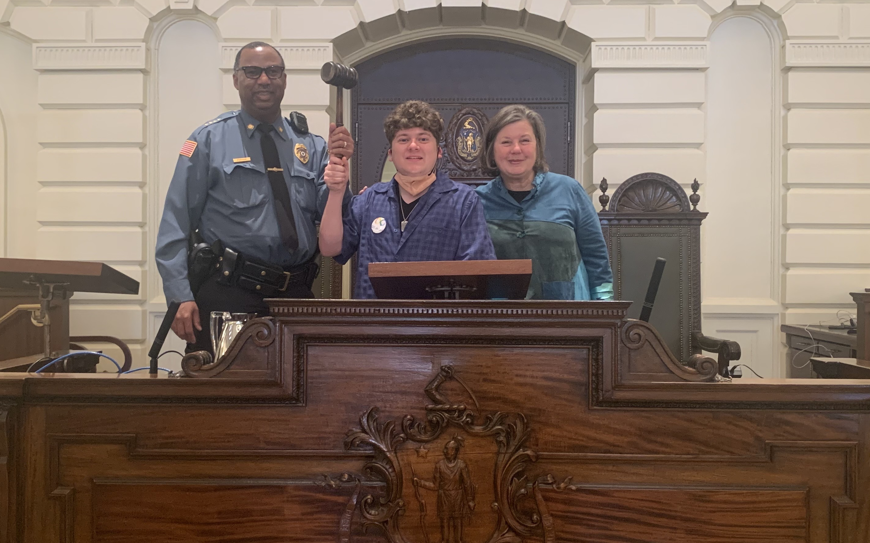 UMass Police Chief Tyrone Parham, Max Callahan and Senator Comerford stand at the Massachusetts Senate Rostrum